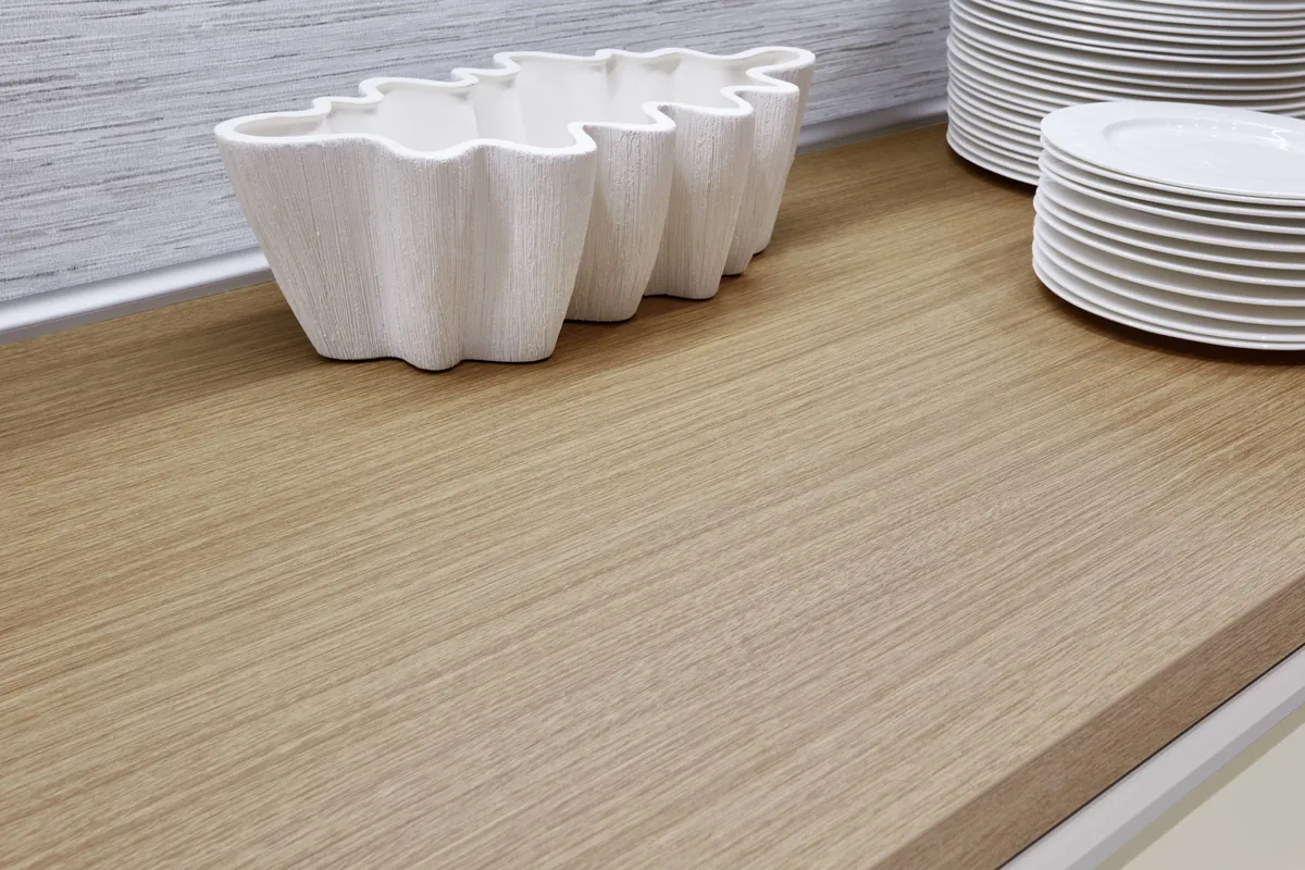 An oak-grain worktop with a white ceramic bowl and stacked plates