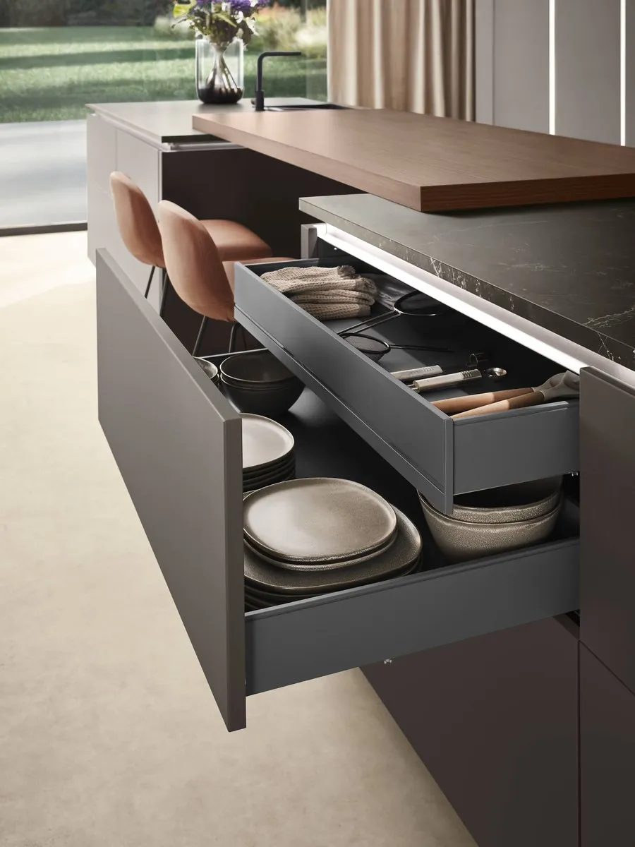 A dark handleless drawer pulled open beneath an island with a timber breakfast bar