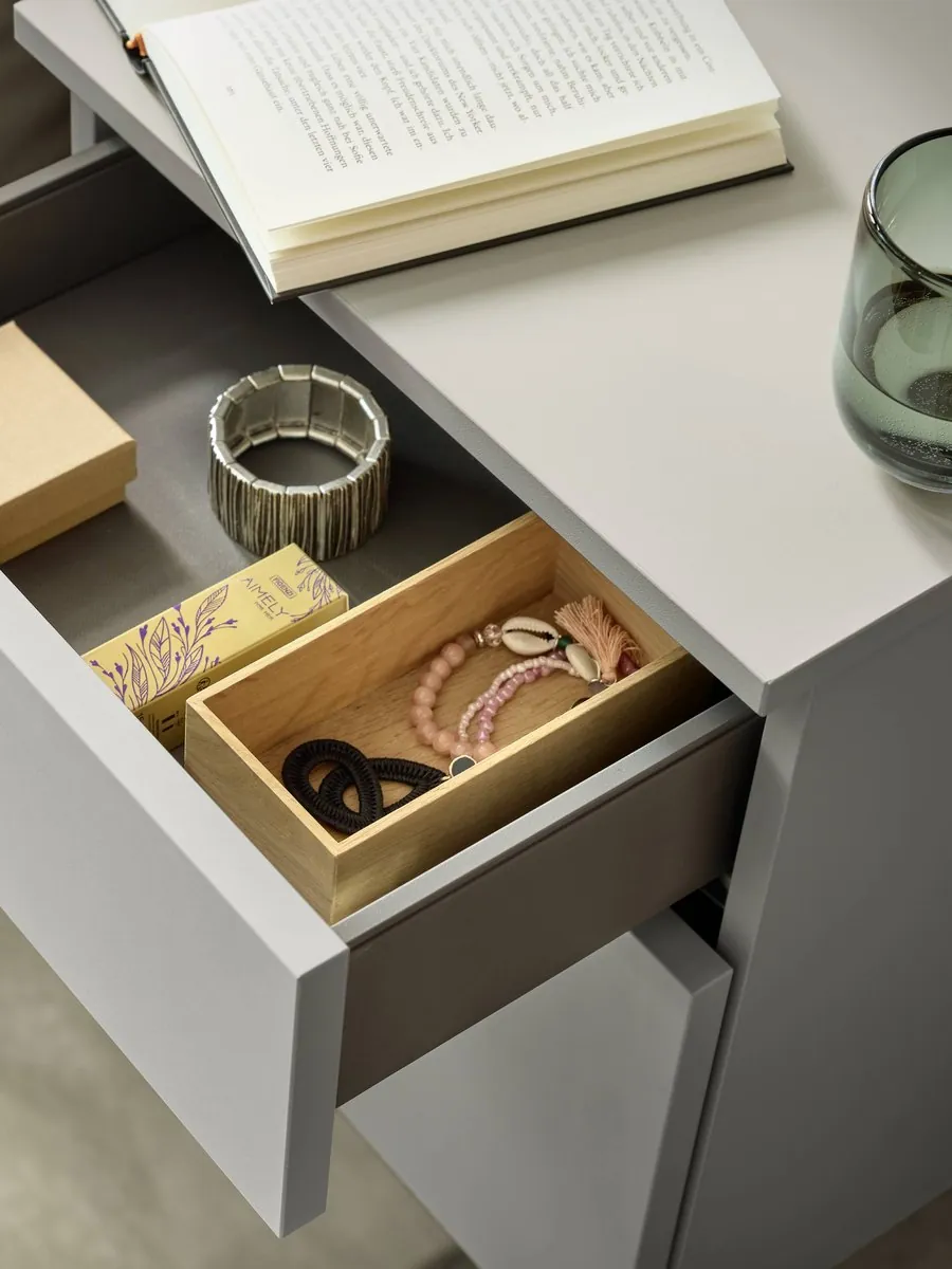 A bedside drawer open on a timber organiser insert