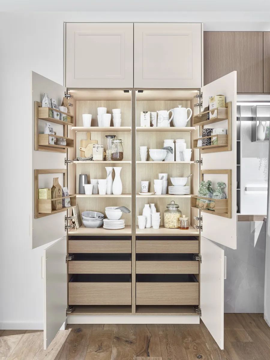 A larder cabinet with its doors open, lined with shelves, door racks and drawers