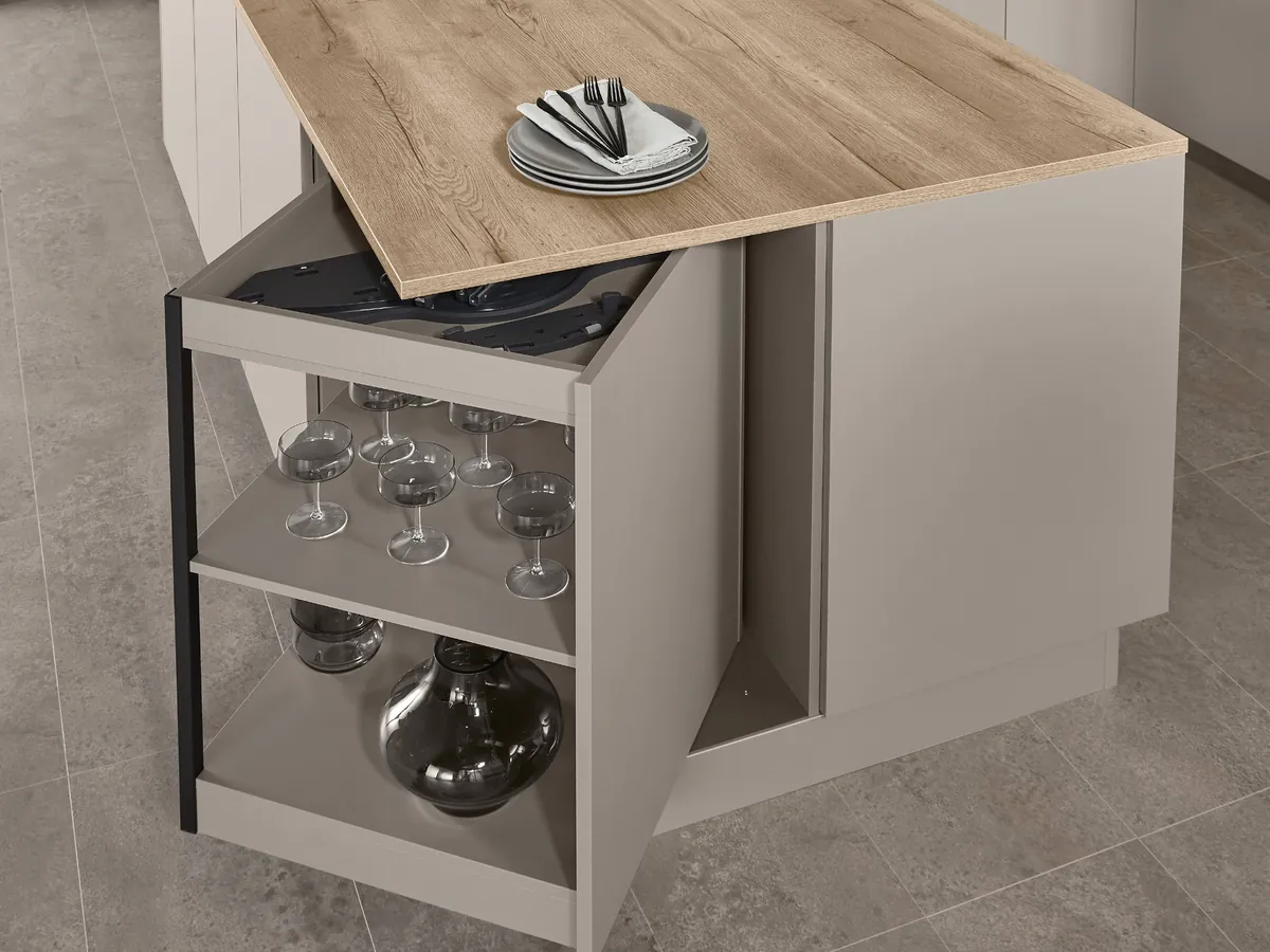 A shelf unit swung out from beneath an island worktop, holding glasses and vases
