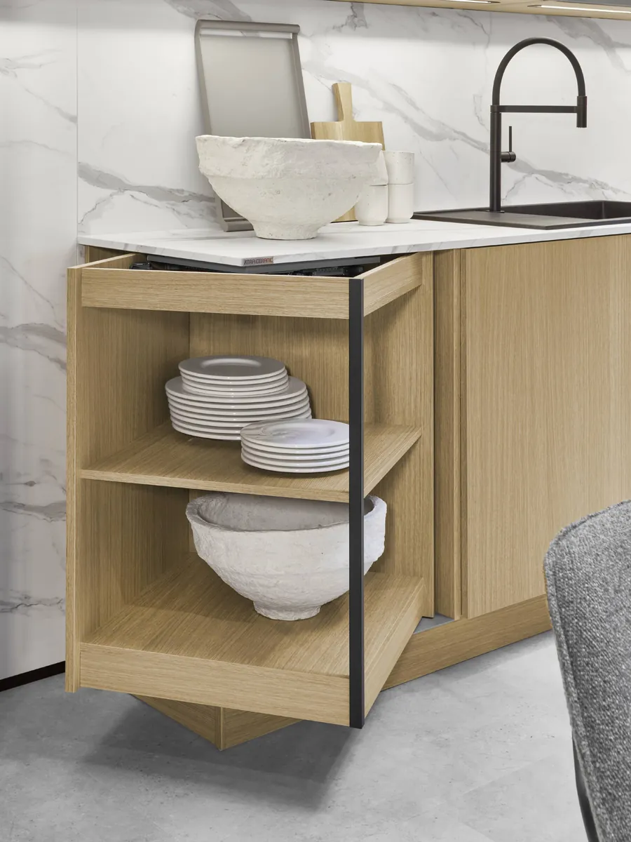 An oak base unit with its shelves swung out, holding plates and bowls